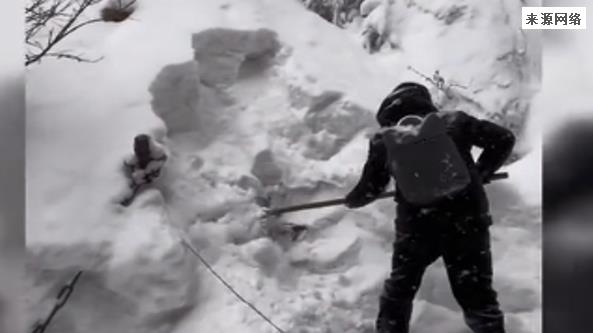 男子脚踩着40cm的积雪边铲雪边登山